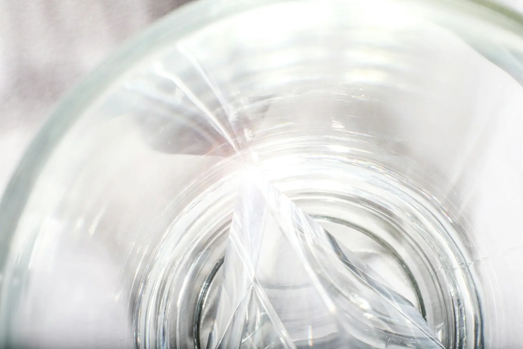 Clear glass ripples bending soft white light into translucent arcs